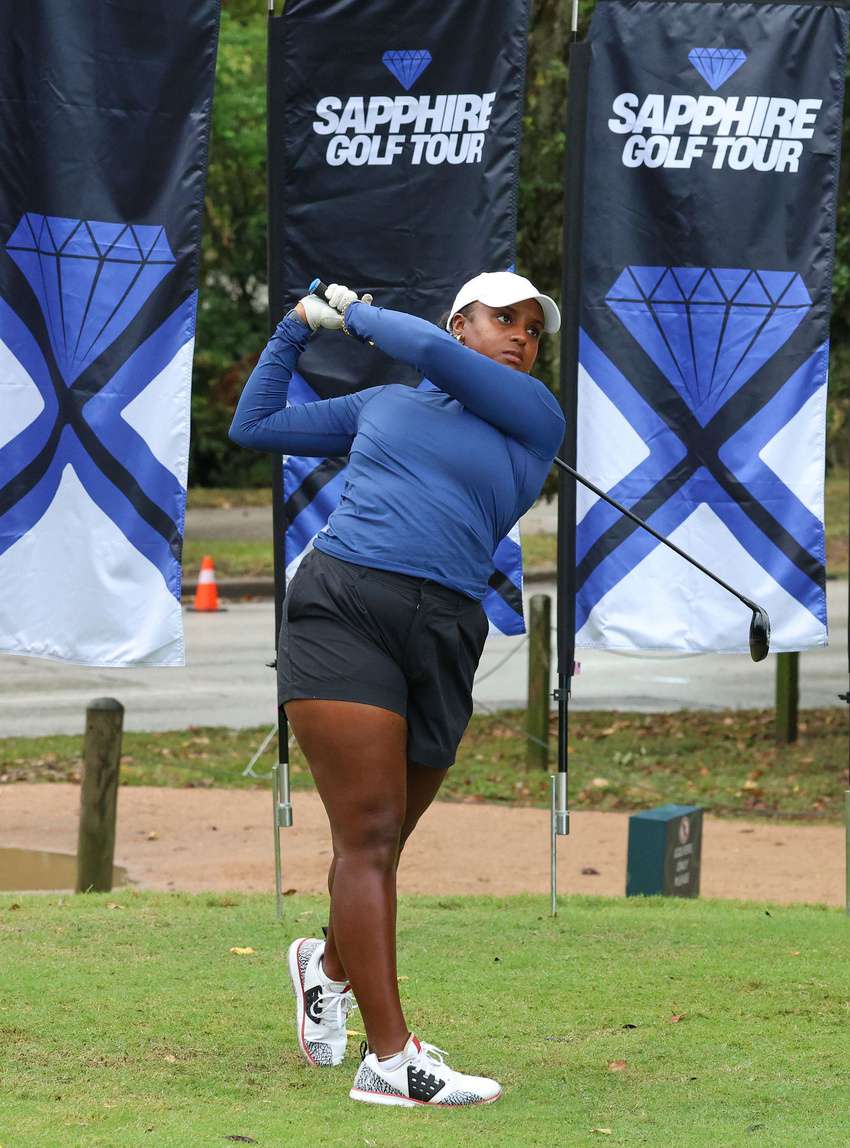 A Sapphire Golf Tour player completing her swing in front of Sapphire tournament banners